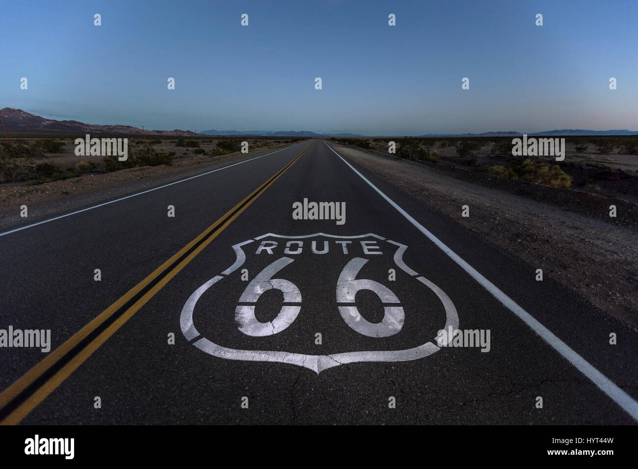 Signe de la chaussée de la route 66 et le désert au crépuscule près de Amboy en Californie. Banque D'Images