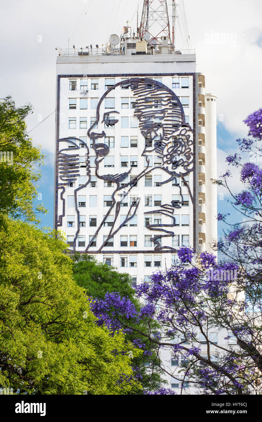 L'installation d'Evita sur le bâtiment du Ministère de la Santé sur l'Avenida 9 de Julio au printemps avec des arbres Jacaranda. Buenos Aires, Argentine. Banque D'Images