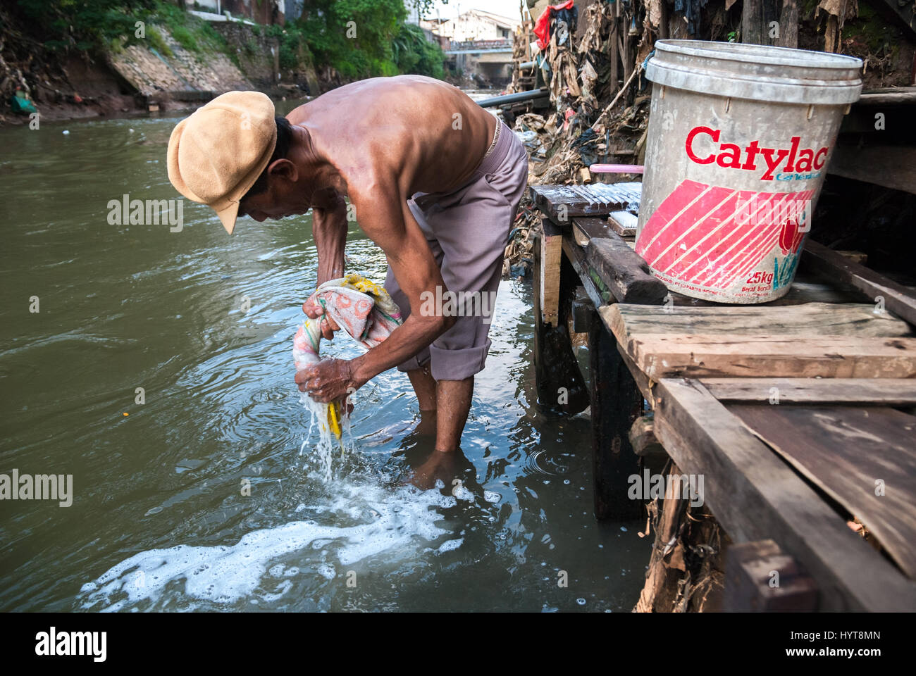 Un homme lave une serviette sur la rivière Ciliwung dans la région de Bukit Duri, Jakarta, Indonésie. Banque D'Images