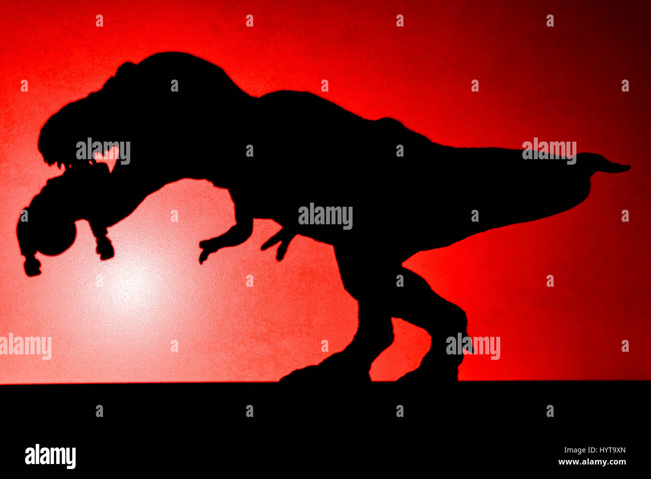 Ombre de tyrannosaurus mordant un corps sur le mur en rouge aucun logo ou marque déposée Banque D'Images