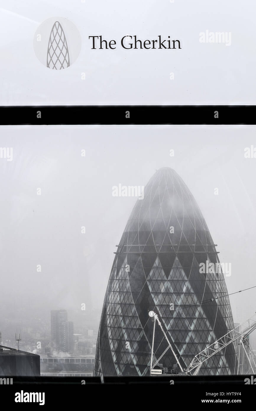 Vue sur le Gherkin à travers une fenêtre de l'édifice, catégorie gratte-ciel Walkie-Talkie à 20 Fenchurch Street, City of London, England, sur un matin brumeux. Banque D'Images