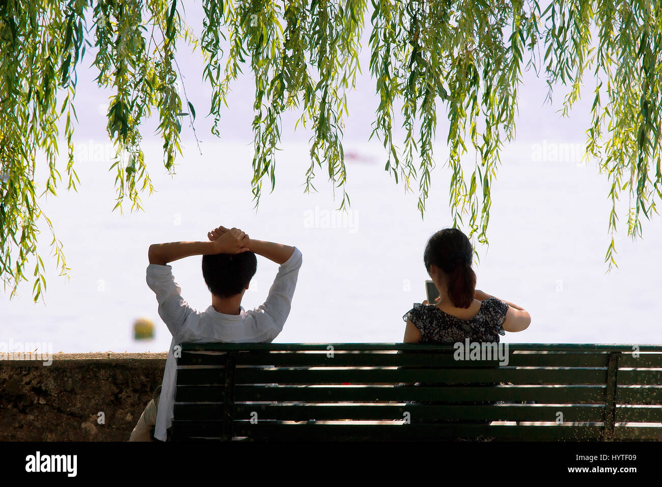 Jeune couple assis sur le banc au bord du Lac Léman embankment à Lausanne, Suisse. Banque D'Images