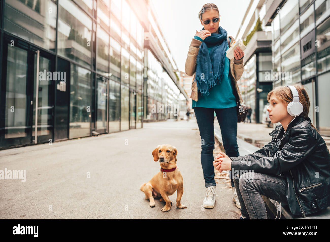 L'écoute de la musique sur le casque fille tandis que la mère et son chien debout à côté Banque D'Images L'écoute de la musique sur le casque fille tandis que la mère et son chien debout à côté Banque D'Images