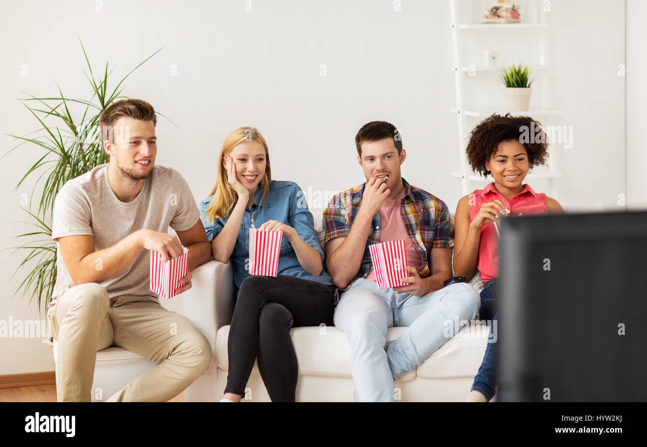 Happy friends with popcorn devant la télé à la maison Banque D'Images