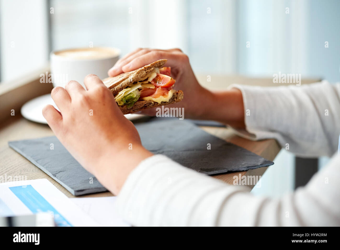 Woman eating sandwich panini au saumon au restaurant Banque D'Images