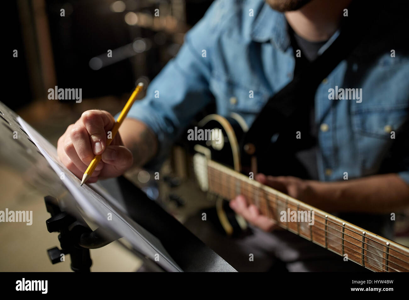 Man with guitar écrit au livre de la musique au studio Banque D'Images