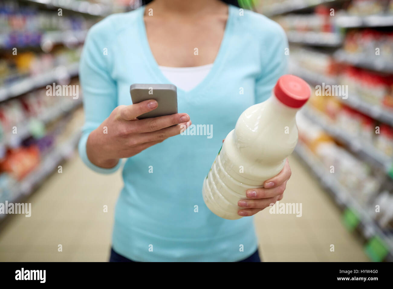 Woman with smartphone acheter du lait au supermarché Banque D'Images