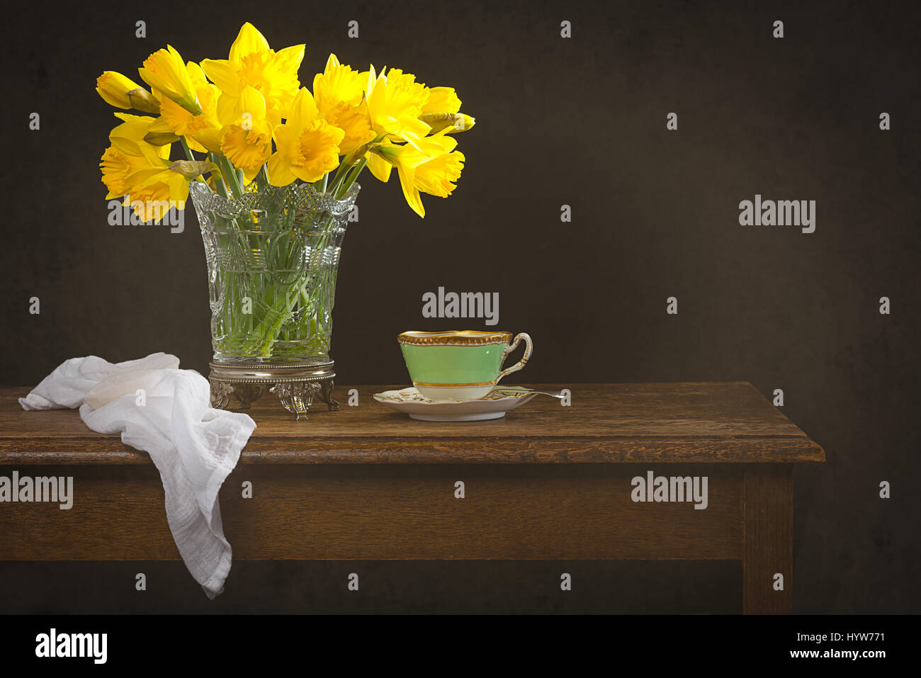 Nature morte avec un vase en verre rempli de jonquilles printemps sur table rustique Banque D'Images