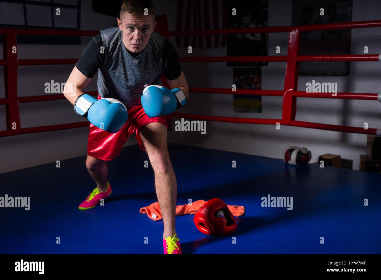Sporty male boxer dans des gants de boxe se lève et se prépare pour la bataille dans les ring de boxe dans une salle de sport Banque D'Images
