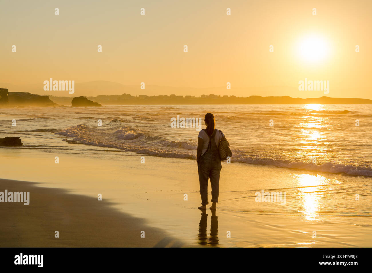 Femme de marcher seul en mer pendant le coucher du soleil à Beach Banque D'Images