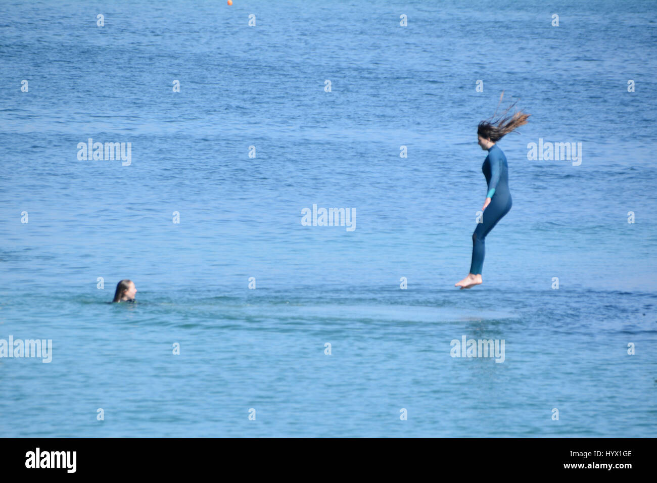 Mousehole, Cornwall, UK. 7 avril 2017. Météo britannique. Après-midi ensoleillé à Mousehole, avec les filles de sauter les murs du port dans la mer. Crédit : Simon Maycock/Alamy Live News Banque D'Images