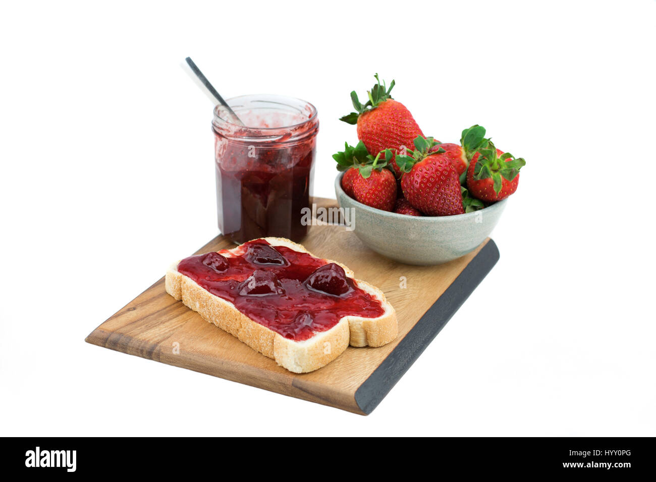 Du pain avec de la confiture de fraise sur une planche de bois. Délicieux petit-déjeuner. Fraise mûre, isolé sur fond blanc. Banque D'Images