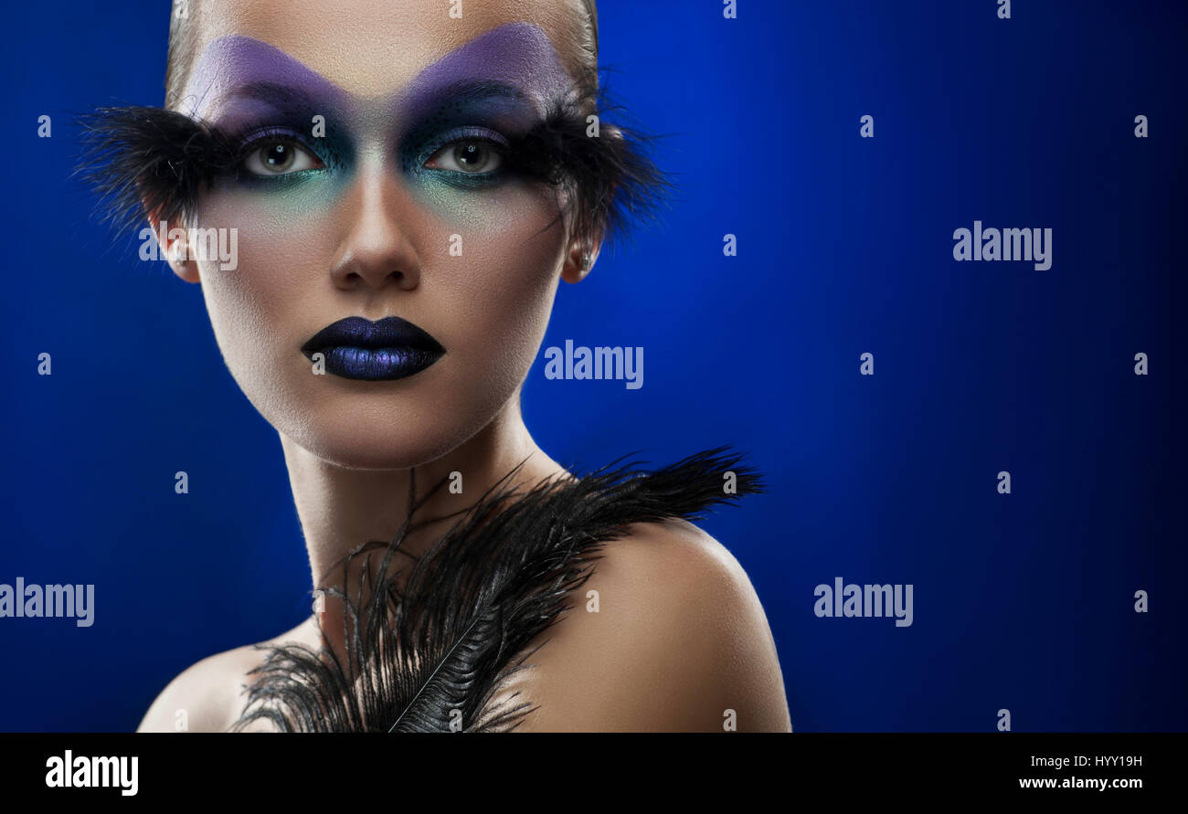L'espace beauté. Portrait horizontal d'une jeune femme portant maquillage  artistique professionnel avec des plumes contre fond bleu Photo Stock -  Alamy