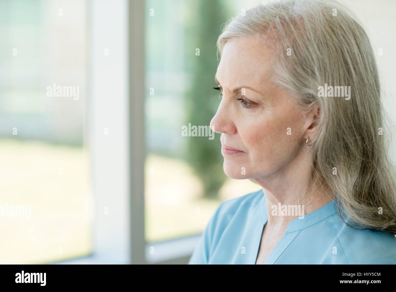 Senior woman looking through window. Banque D'Images