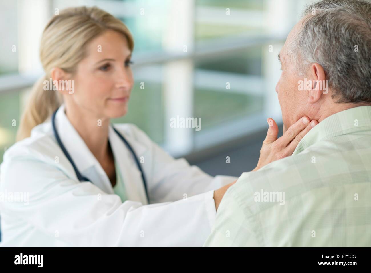 Femme médecin senior toucher le cou de l'homme. Banque D'Images