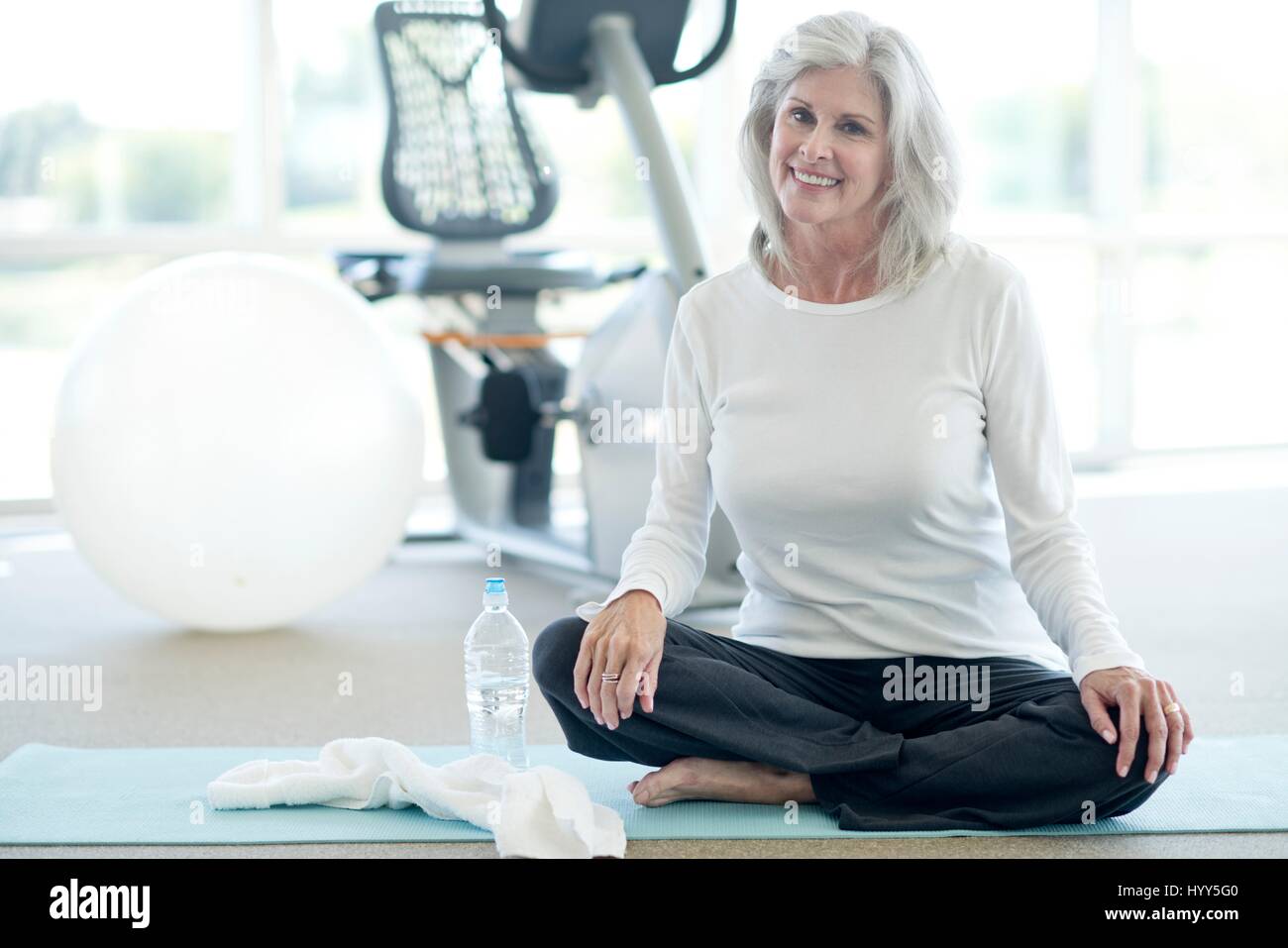 Senior woman sitting cross legged dans une salle de sport. Banque D'Images