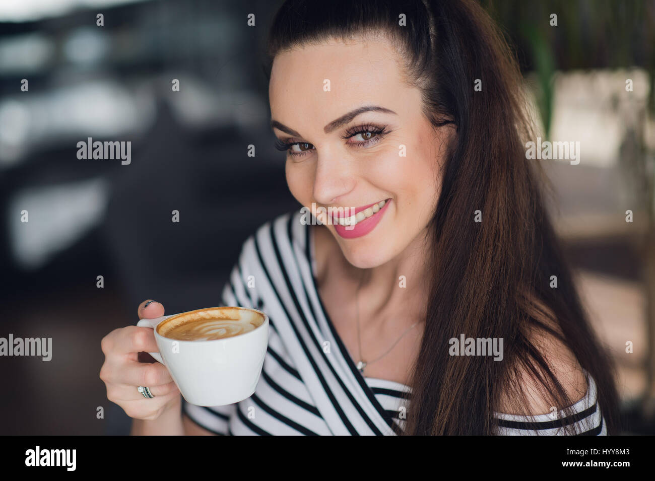 Un close-up portrait d'une femme avec un sourire parfait avec une tasse de cappuccino ou de café. Les dents blanches et le maquillage. Banque D'Images