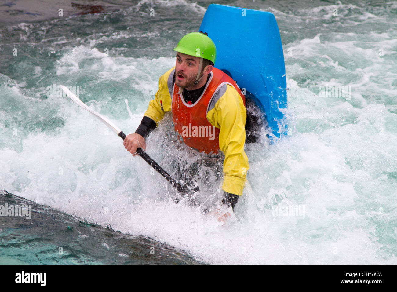 Adolescent dans un kayak pendillant verticalement dans l'eau qui coule sur le point de faire un rouleau Banque D'Images