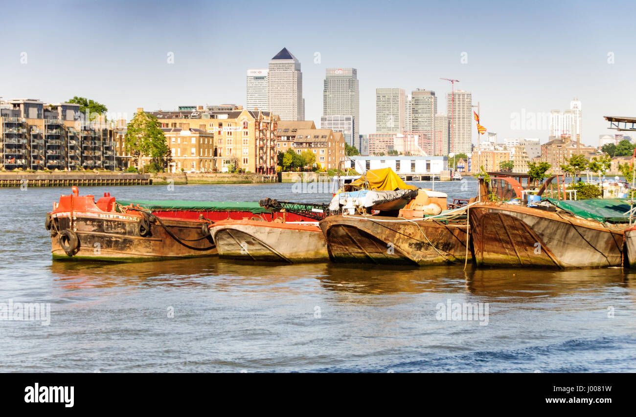 L'horizon de quartier des Docklands de Londres s'élève au-dessus de vieux waterhouses industrielle et de barges sur la tamise à bermondsey. Banque D'Images