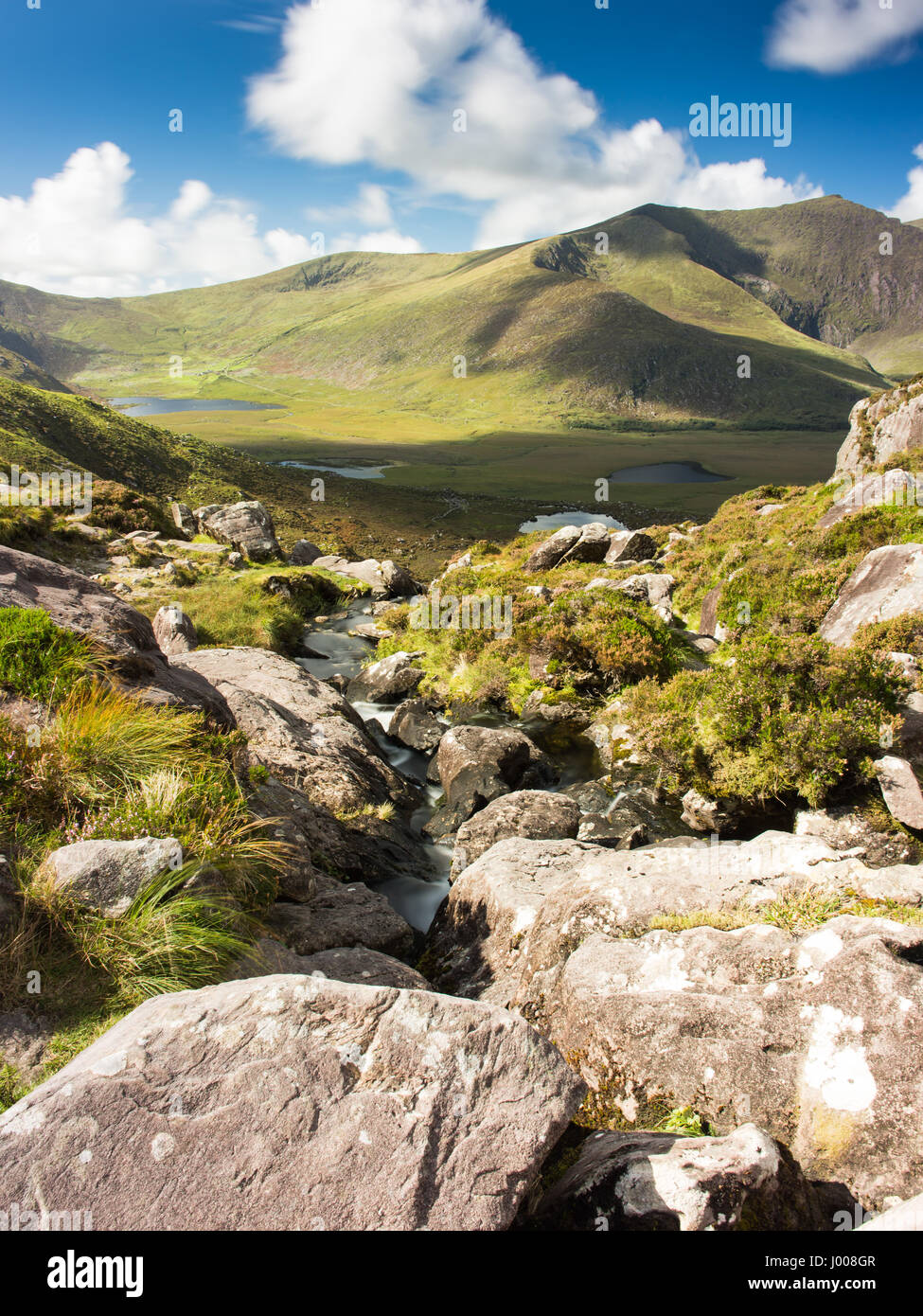Un petit ruisseau de montagne rocheuse tombe de Pedlar's Lake vers l'Owenmore vallée, avec Brandon Mountain derrière, près de l'Conor Pass à travers le mo Banque D'Images
