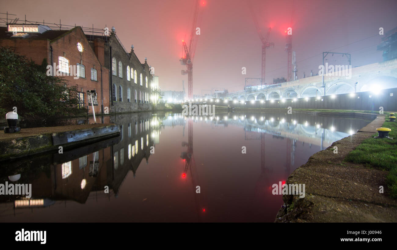 Londres, Angleterre, Royaume Uni - 30 décembre 2016 : Entrepôts, grues à tour et la ligne de chemin de fer du nord de Londres se reflètent dans le Regent's Canal entre Kentis Banque D'Images