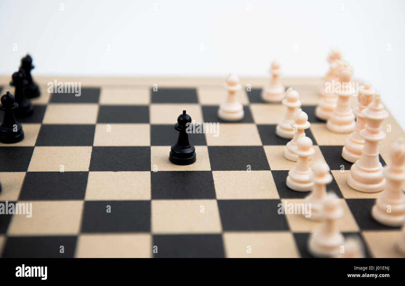 Jeu d'échecs avec pion noir prêt à attaquer les pions blancs sur un échiquier en bois Banque D'Images