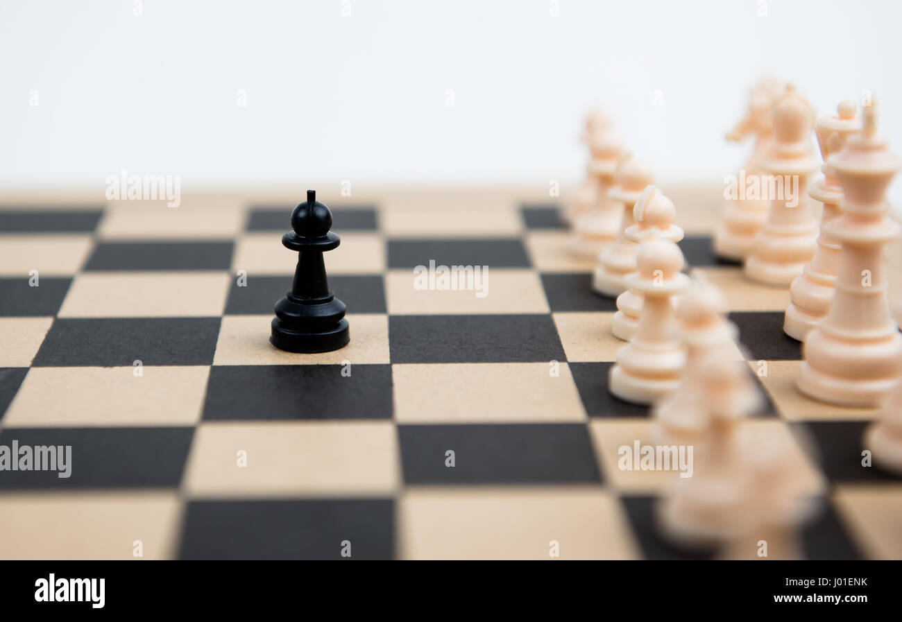 Jeu d'échecs avec pion noir prêt à attaquer les pions blancs sur un échiquier en bois Banque D'Images