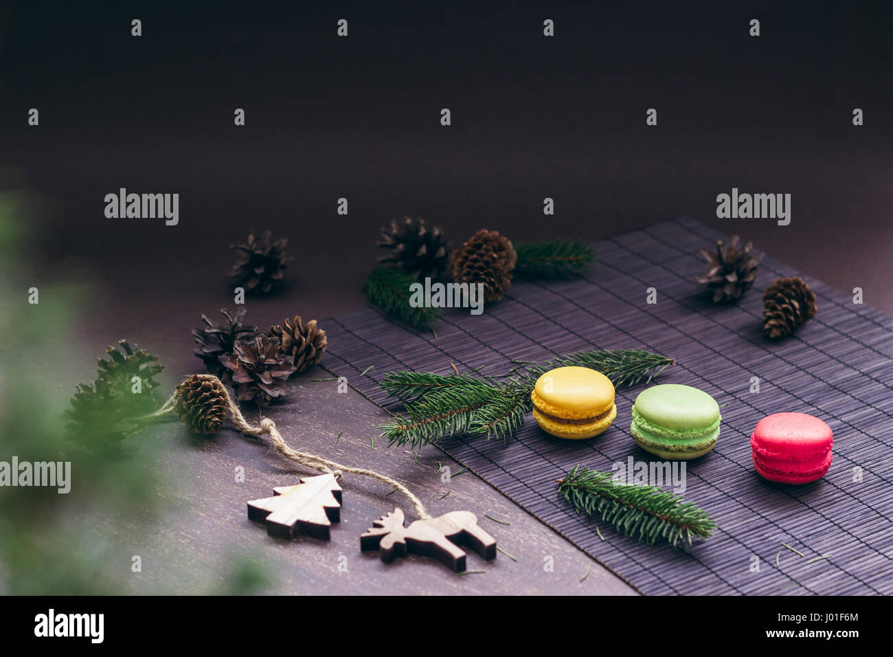 Trois macarons dans une rangée sur la table avec des branches de sapins, des cônes et des ornements de Noël Banque D'Images