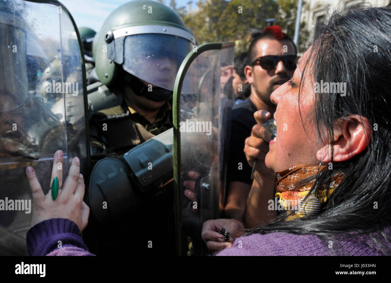 Une femme pousse des manifestants contre les boucliers de la police chilienne, connue sous le nom de Carabiniers, à Santiago, Chili. Banque D'Images