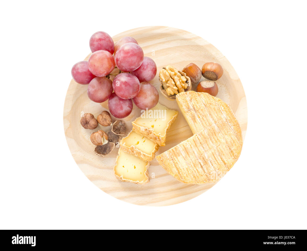 Soft croûte lavée, noisettes, noix et raisins rouges sur la planche de bois texturés top view isolated on white Banque D'Images