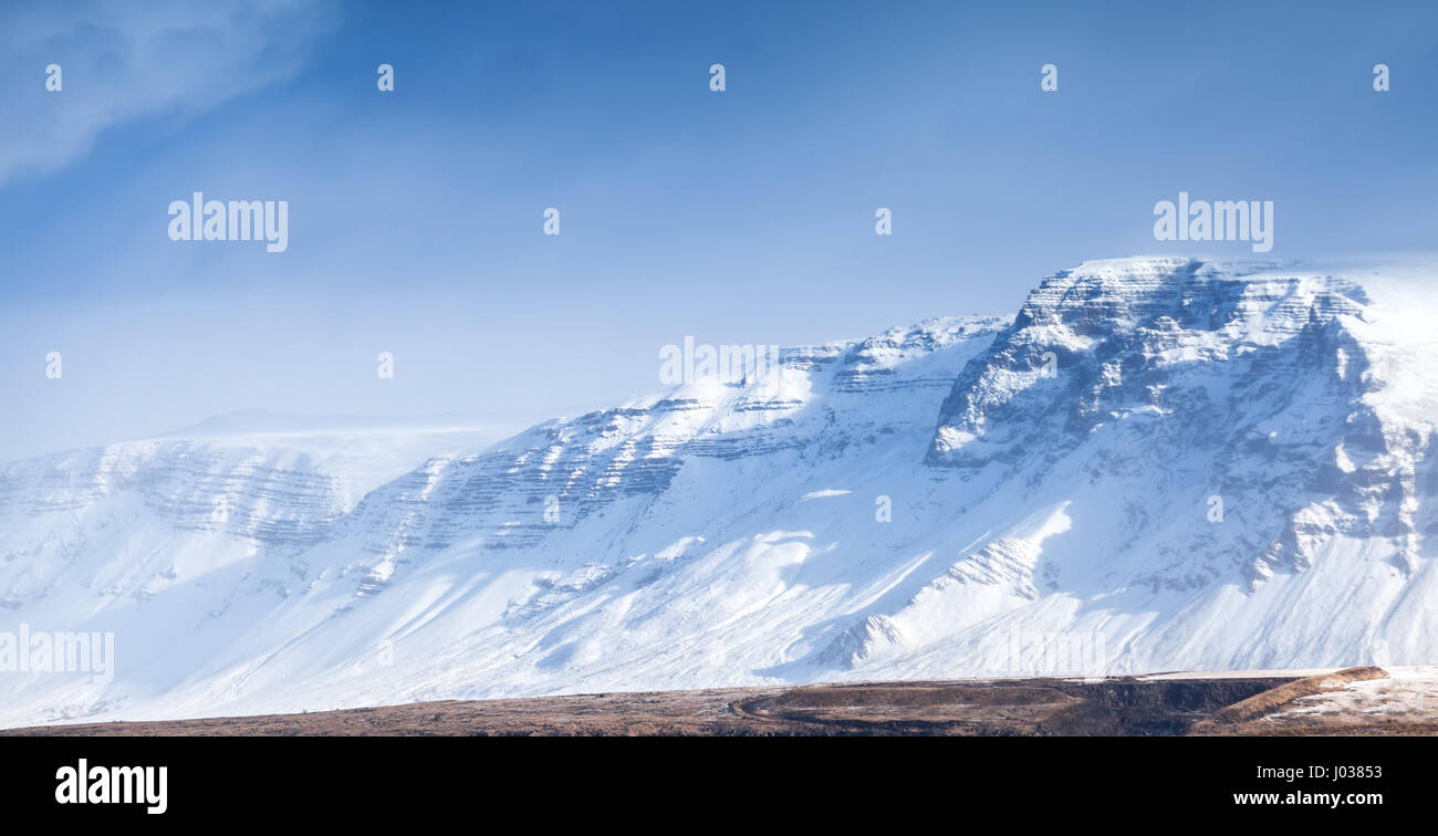 Paysage islandais côtières avec montagnes enneigées sous le bleu ciel nuageux. District de Reykjavik, Islande Banque D'Images