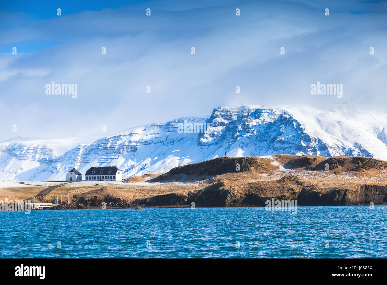 Paysage islandais côtières avec les montagnes enneigées et petit salon chambre sous ciel bleu dramatique. Région de Reykjavik, Islande Banque D'Images