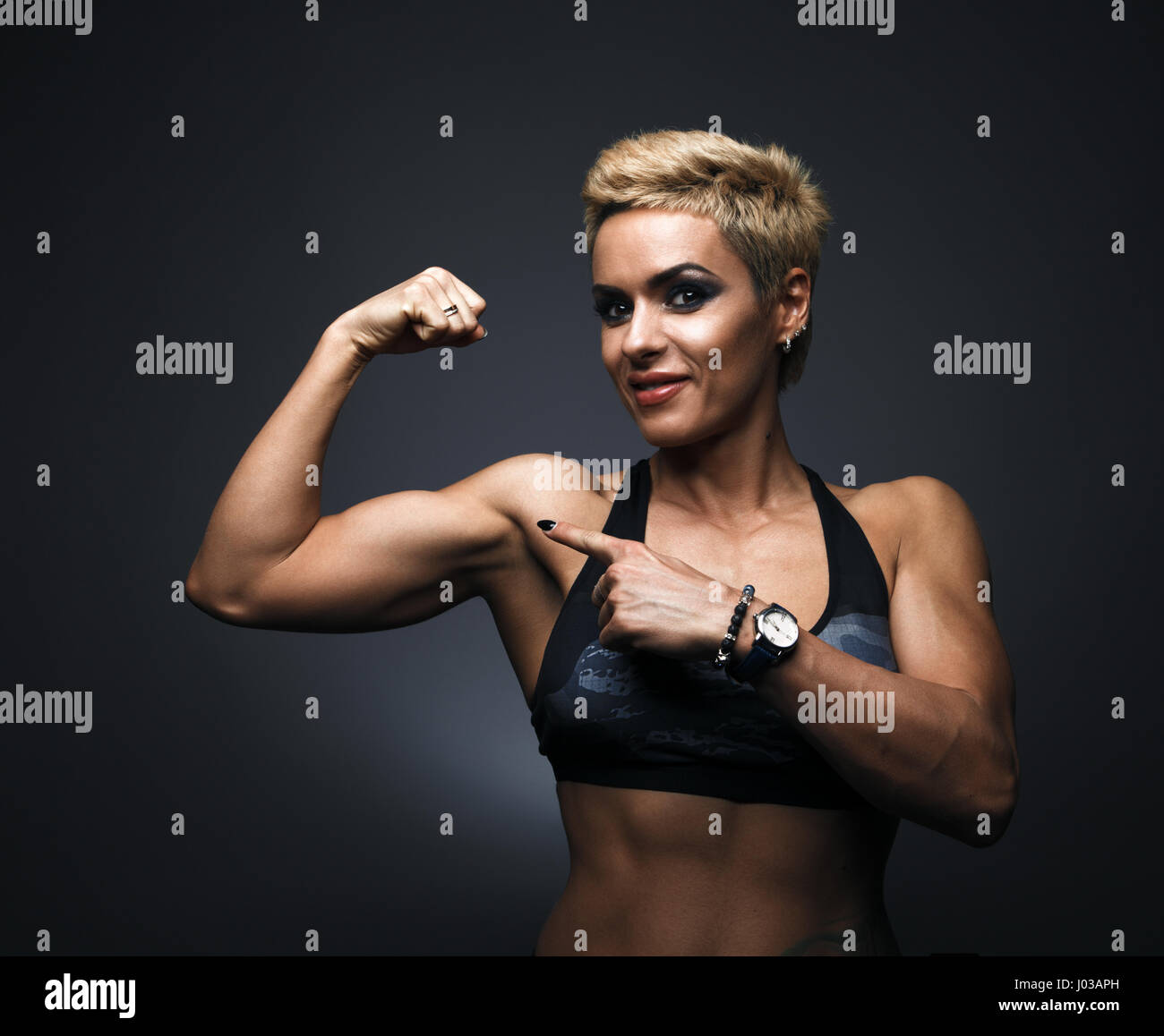 Nom smiling sporty woman démontrant des biceps Banque D'Images