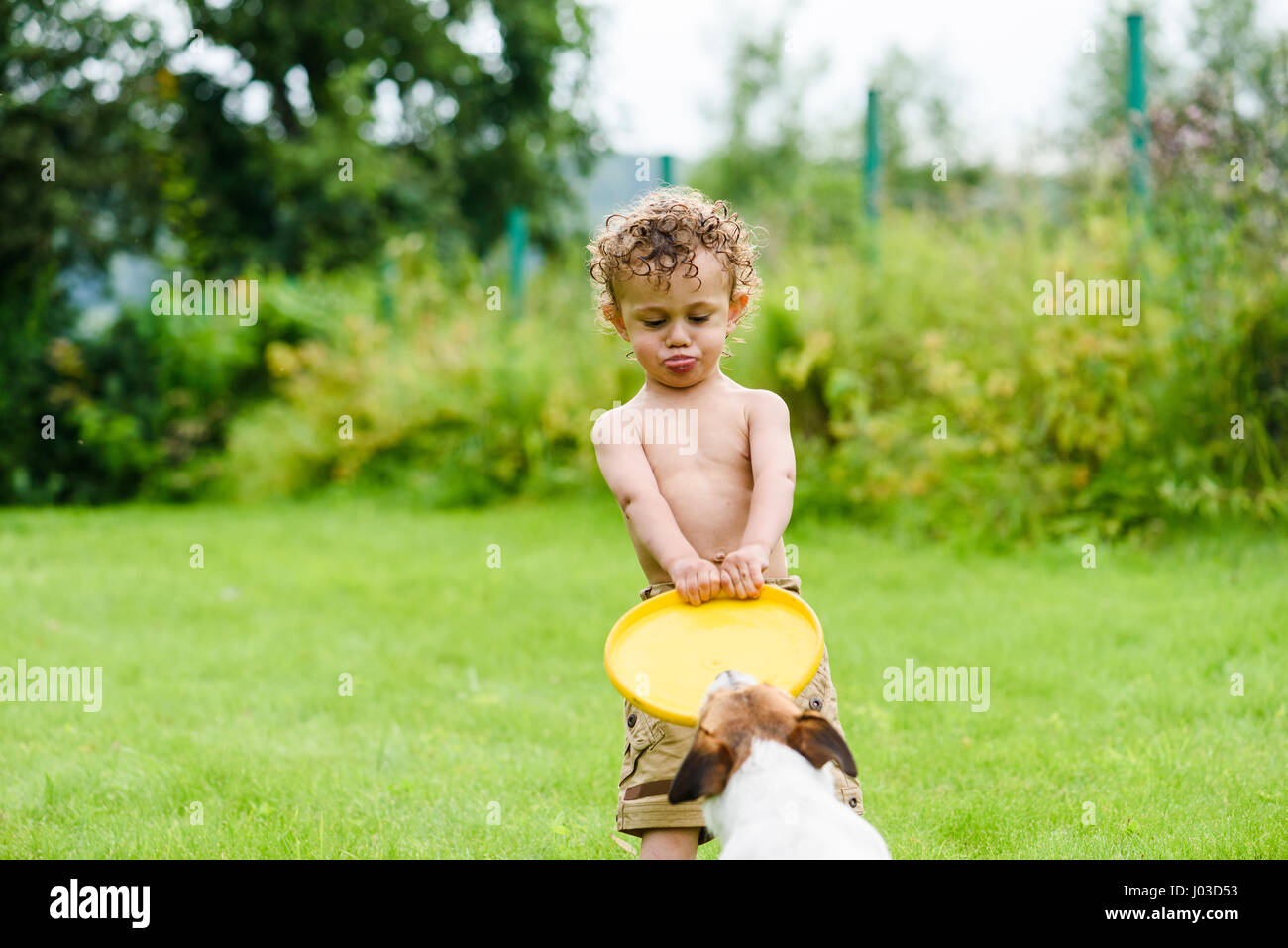 Garçon avec drôle de visage expression et langue Playing with dog Banque D'Images