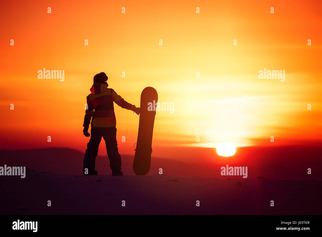 Snowboarder femme silhouette sur fond coucher de soleil Banque D'Images