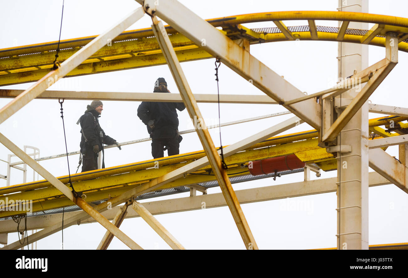 Les hommes d'entretien réparation d'une de montagne russe dans un parc d'attractions. Banque D'Images