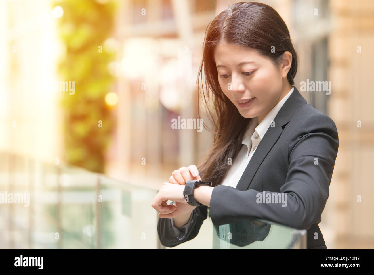Les hommes et la technologie concept. Happy business woman looking at sa smartwatch. mixed race chinoise asiatique sur fond flou. Banque D'Images