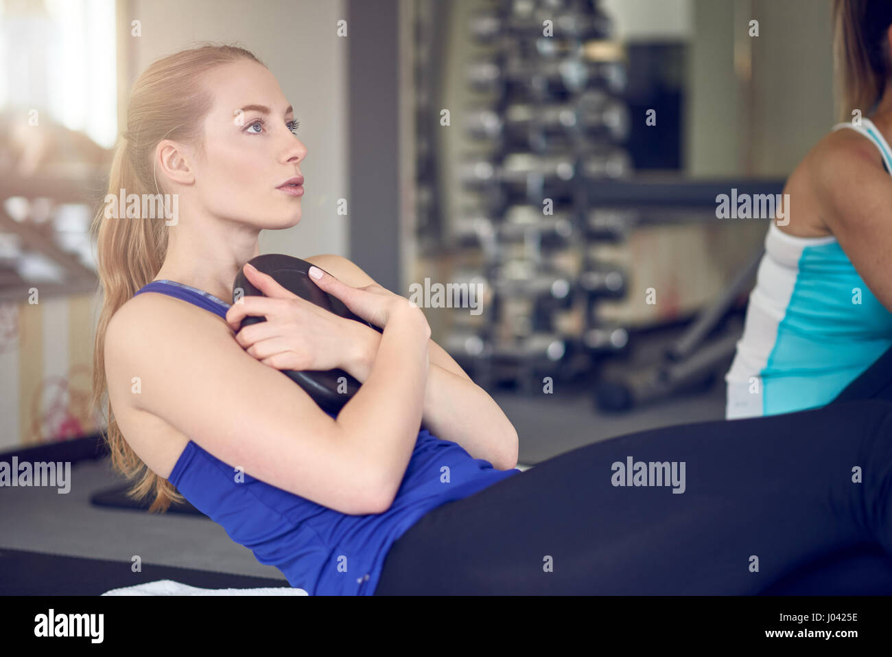 Paire de jeunes femmes adultes faisant des exercices des muscles abdominaux torsion russe poids tout en maintenant Banque D'Images