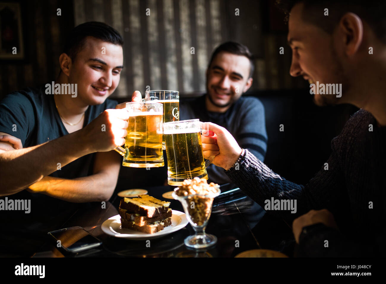 Les gens, les hommes, les loisirs, l'amitié et de fête concept - heureux amis boire une bière et clinking glasses au bar ou au pub Banque D'Images
