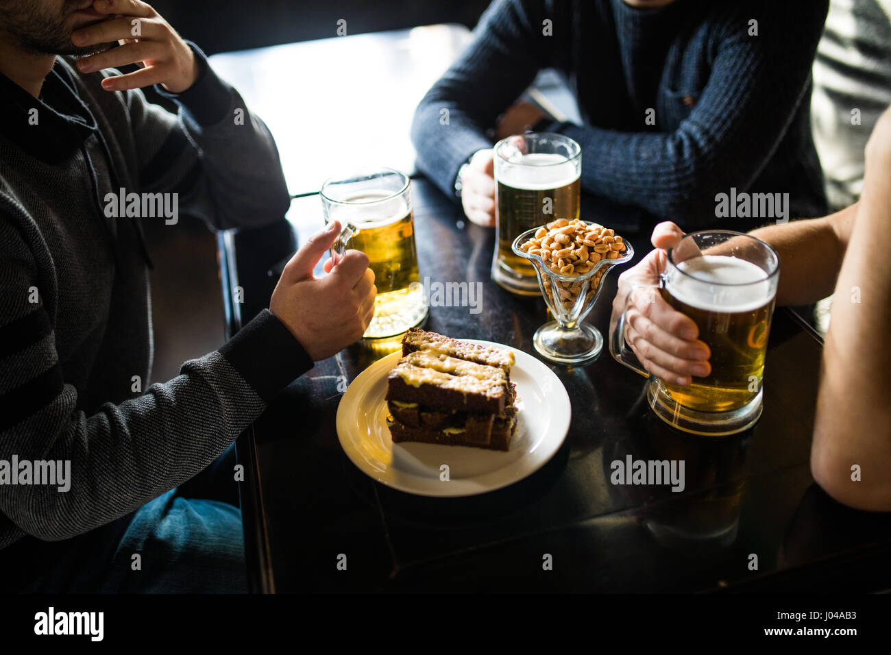 Les gens, les loisirs et les boissons concept - close up of male hands tintement des verres à bière et des bretzels au bar ou au pub Banque D'Images
