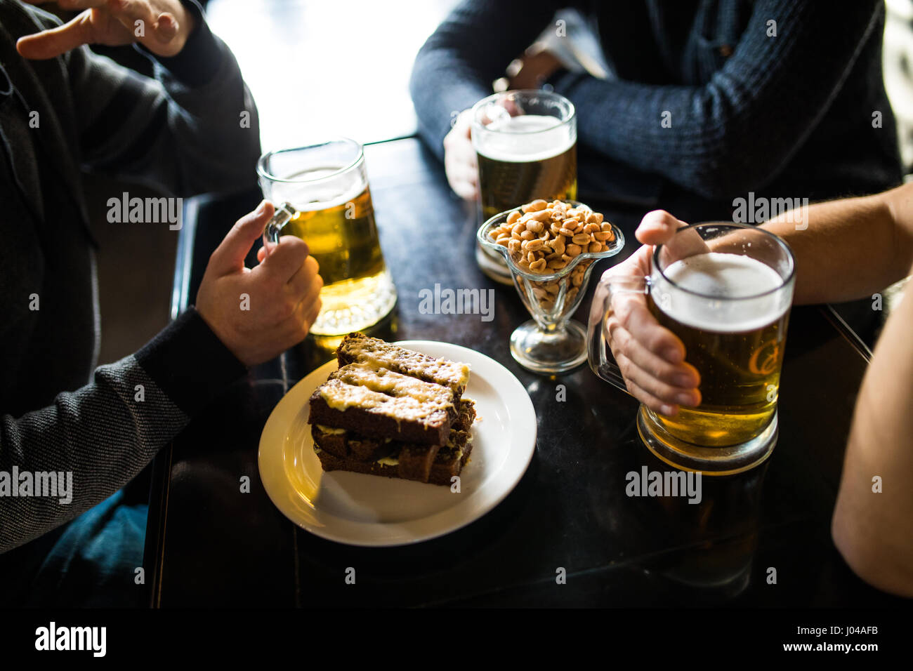 Les gens, les loisirs et les boissons concept - close up of male hands tintement des verres à bière et des bretzels au bar ou au pub Banque D'Images
