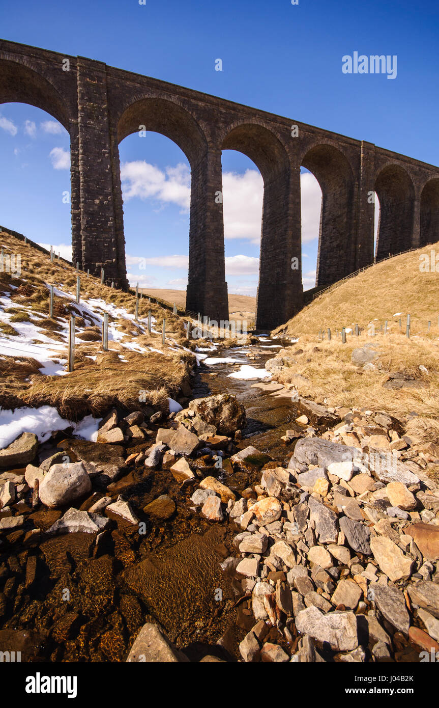 L'Arten Gill Viaduct sur la ligne de chemin de fer s'installer à Carlisle est découpé sur un ciel bleu au-dessus du ruisseau de montagne mouchetée de neige de l'Arten Gill Banque D'Images