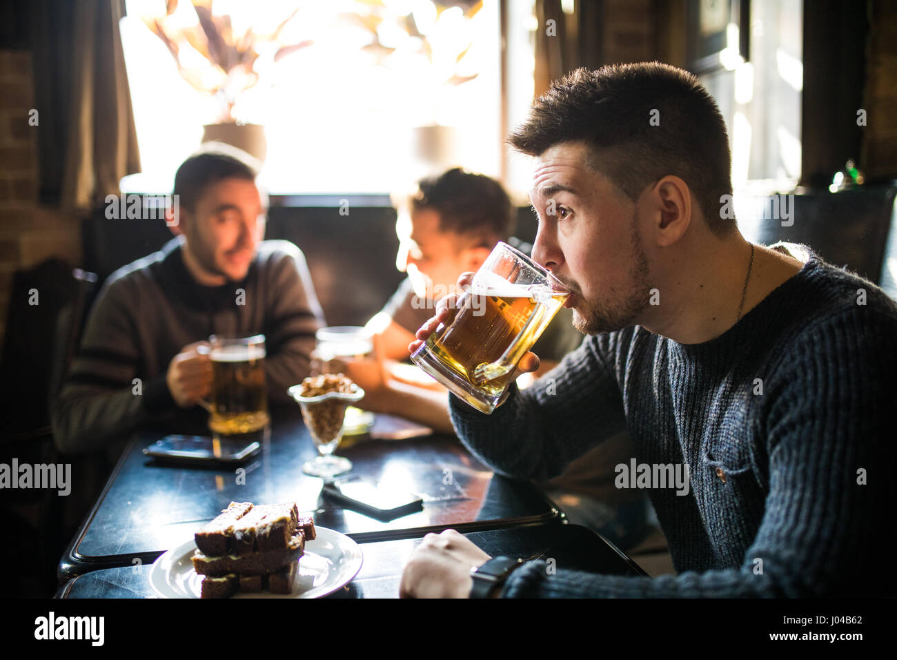 L'homme de boire de la bière devant à discuter entre amis boire dans un pub. Banque D'Images
