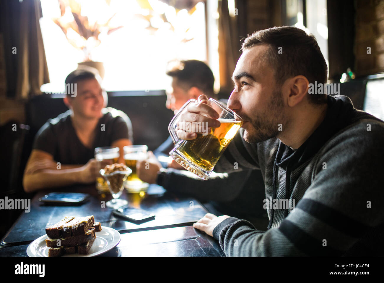 L'homme de boire de la bière devant à discuter entre amis boire dans un pub. Banque D'Images