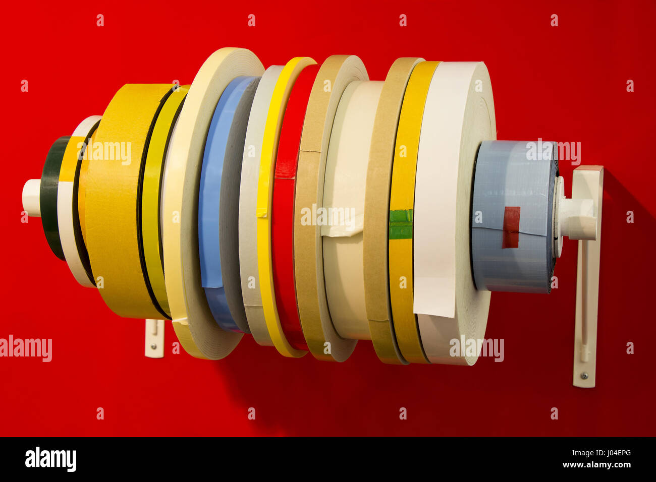 Double ruban adhésif dans diverses ; rouleaux de différents types de ruban sur fond rouge Banque D'Images