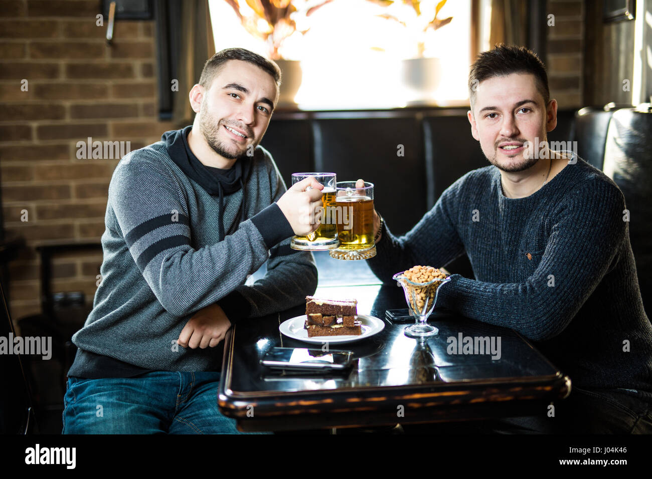 Deux beaux amis dans un pub avec des verres de bière. Banque D'Images