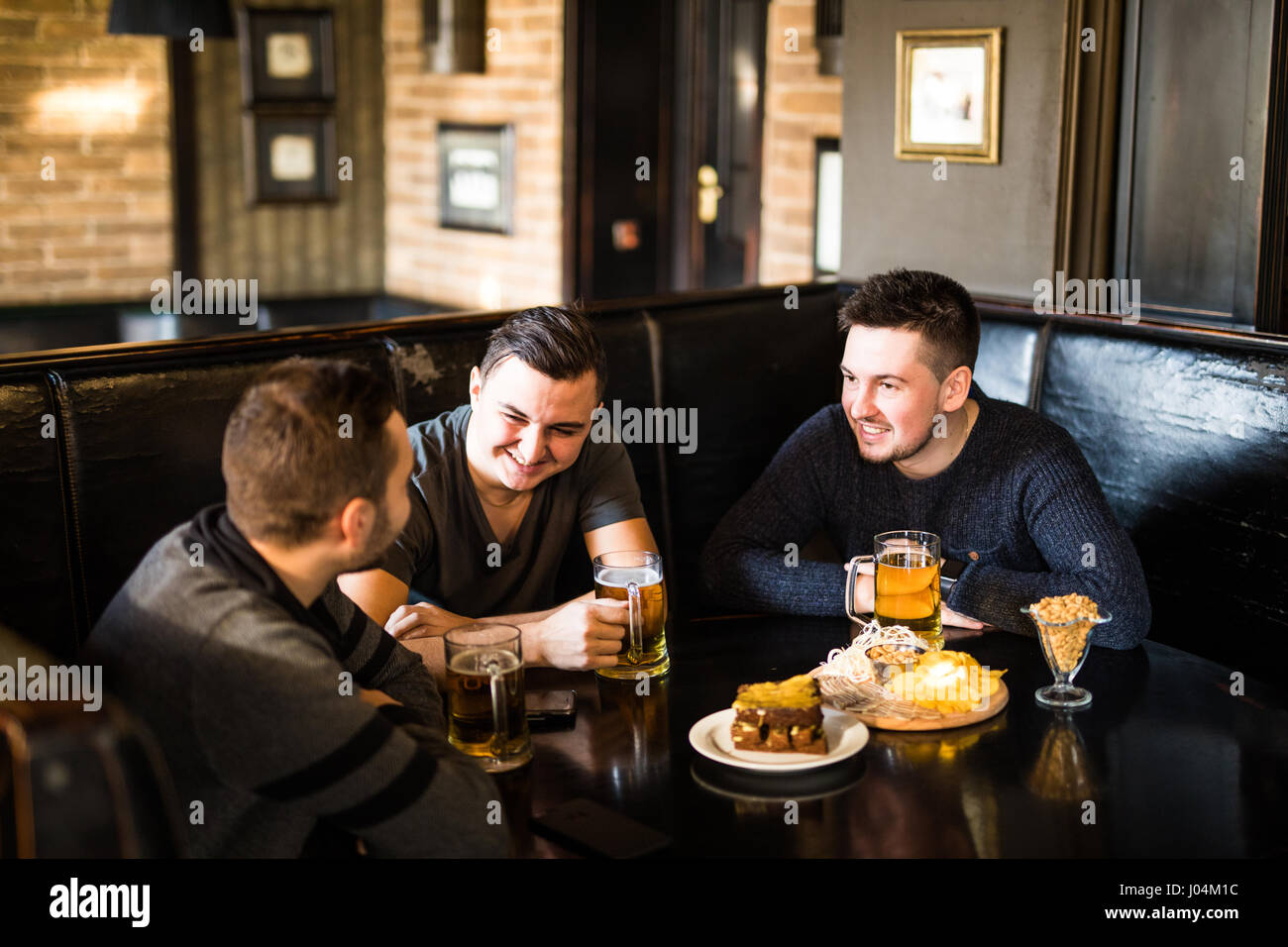 Réunion à la pub. Trois amis heureux de boire une bière au pub Banque D'Images