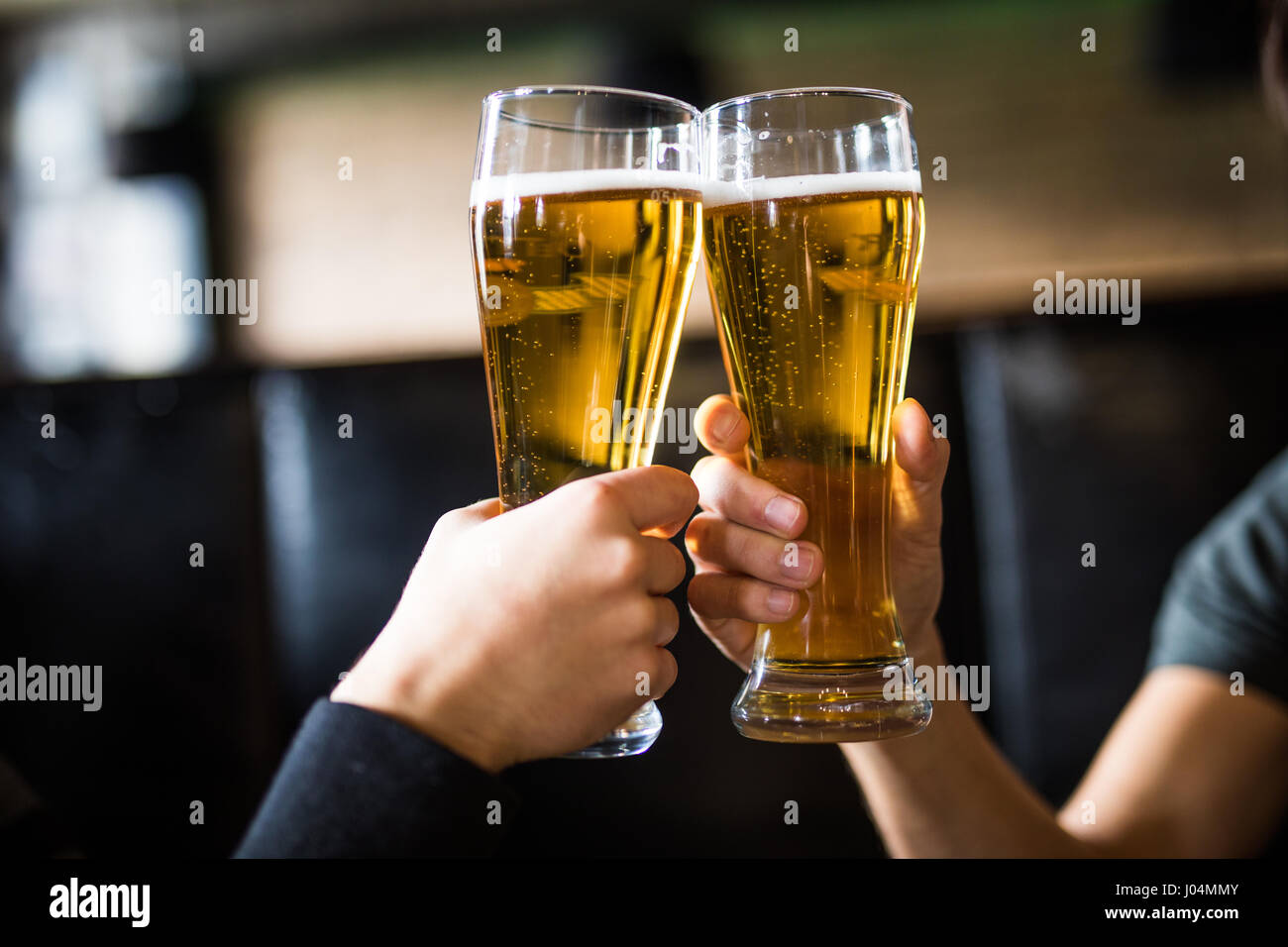 Les hommes avec de la bière cheers dans les verres dans un pub. Banque D'Images