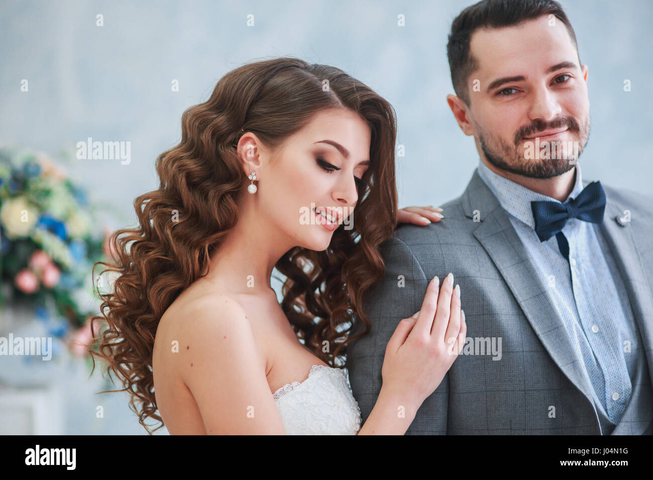 Heureux l'époux et épouse posant sur un studio avec de belles fleurs decor .Couple hugging Banque D'Images Heureux l'époux et épouse posant sur un studio avec de belles fleurs decor .Couple hugging Banque D'Images