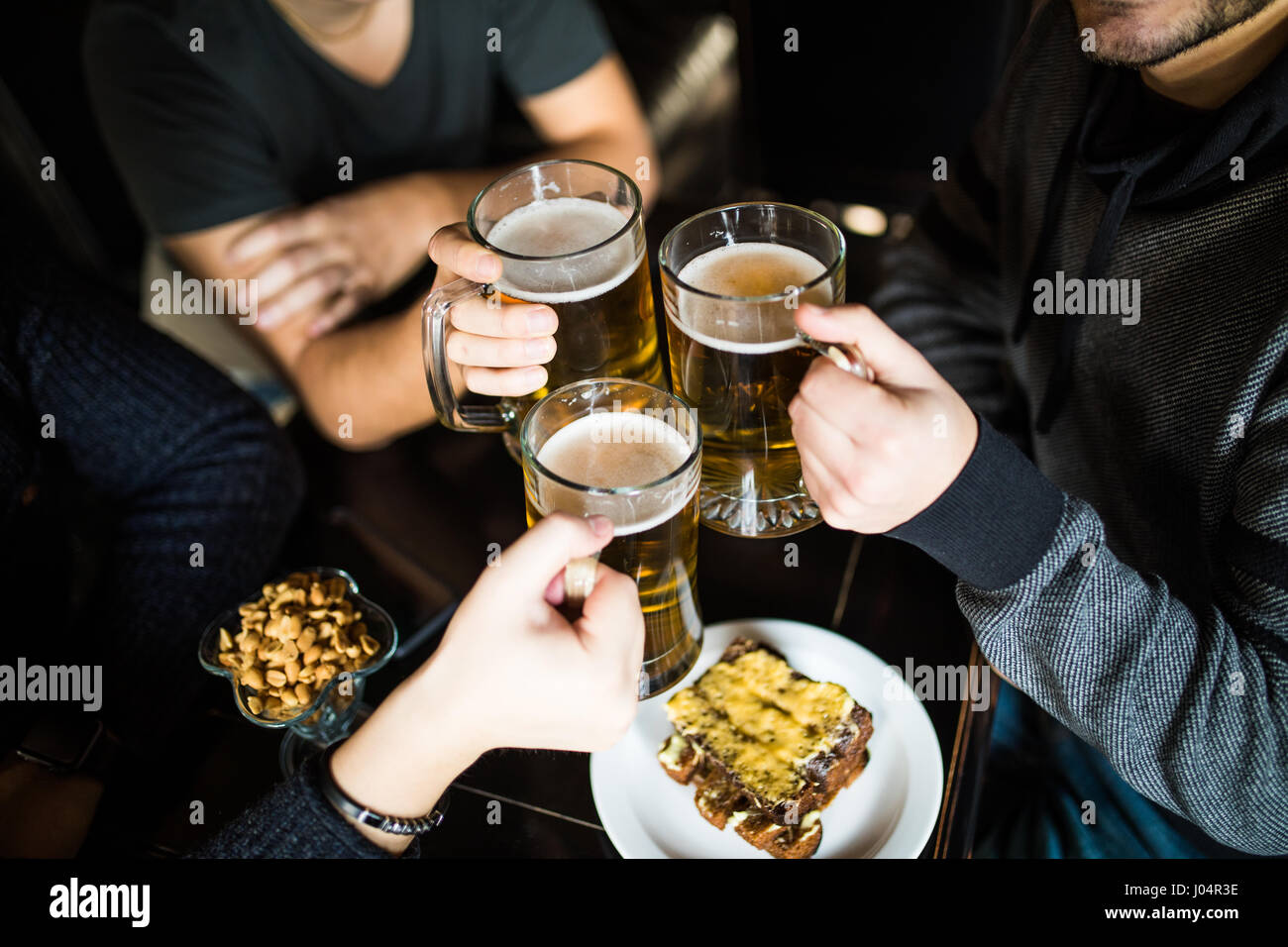 Les gens, les loisirs et les boissons concept - close up of male hands tintement des verres à bière et des bretzels au bar ou au pub Banque D'Images